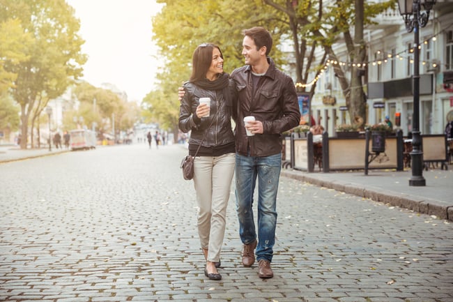 Portrait of a happy romantic couple with coffee walking outdoors in old european city-1