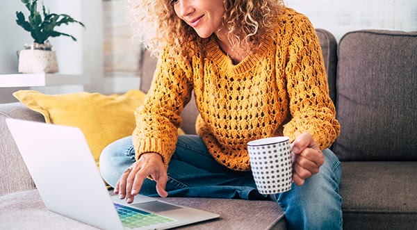 Woman Smiling with Laptop and Coffee - How to Reserve Corporate Housing - What is Corporate Housing